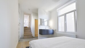 Una camera da letto con un letto grande, una panchina integrata, una toeletta scura e una finestra che lascia entrare luce naturale.
