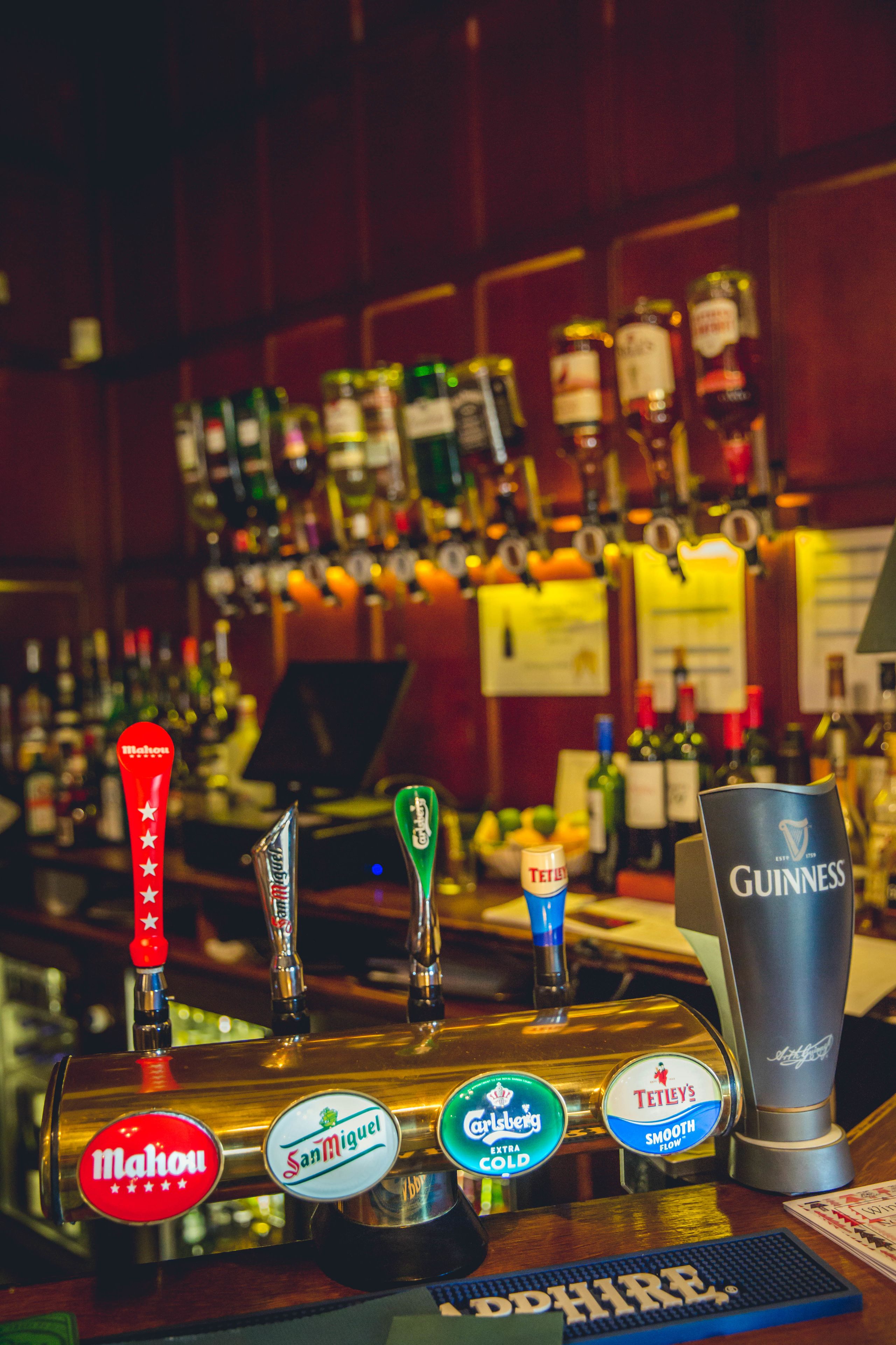 A bar with various beer taps including brands like Mahou, San Miguel, Carlsberg, and Guinness.