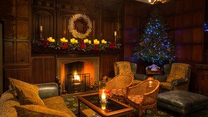 A cozy room with a fireplace, a Christmas tree, and comfortable seating. - Netherwood Hotel & Spa (Grange-over-Sands)