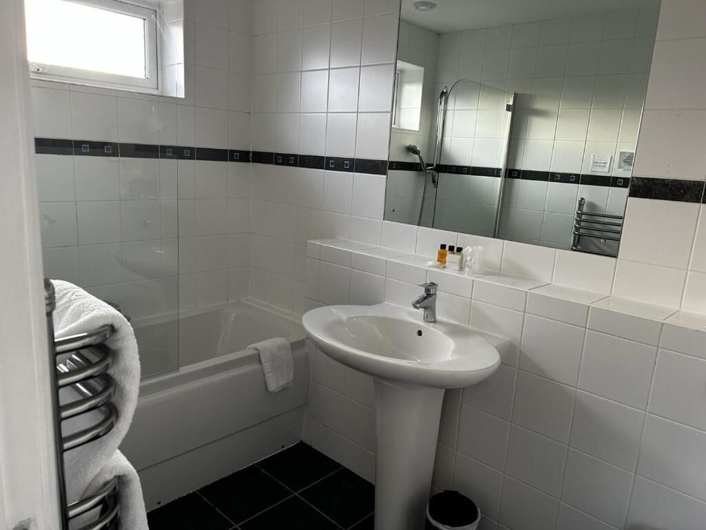 A bathroom with a white sink, a mirror, a towel rack, and a shower.