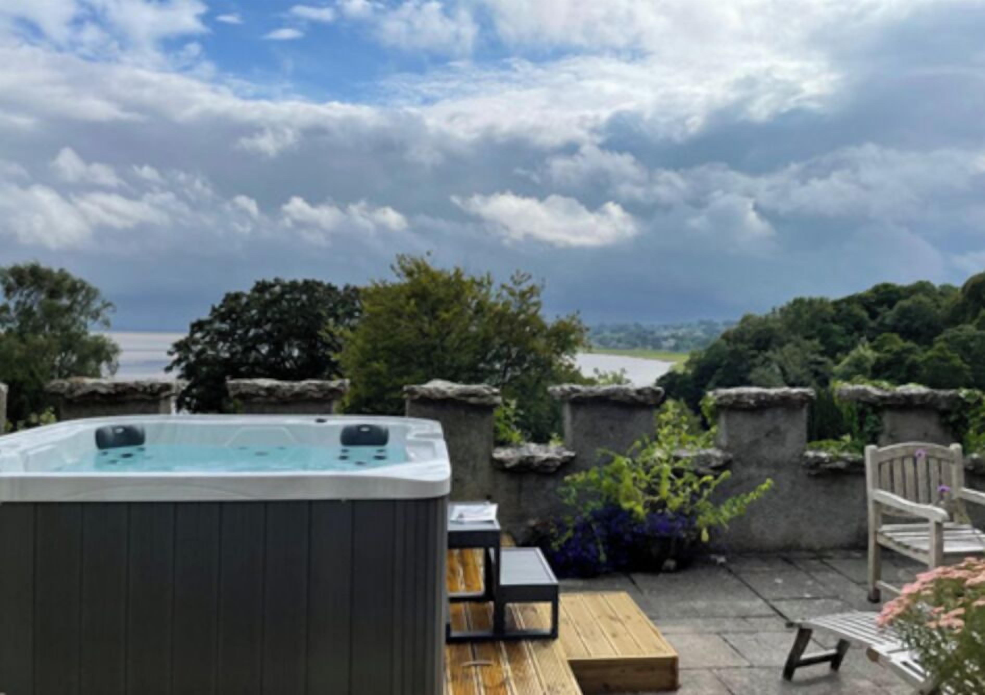 Un jacuzzi en un patio con vistas a un cuerpo de agua y árboles.