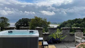 Un jacuzzi en un patio con vistas a un cuerpo de agua y árboles.