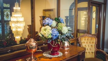 A wooden table with a vase of flowers, a copper teapot, and a glass pitcher.