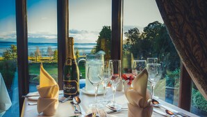 A table set for dining with a bottle of champagne, glasses, and cutlery. - Netherwood Hotel & Spa (Grange-over-Sands)