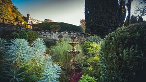 A garden with a stone wall, a fountain, and various plants. - Netherwood Hotel & Spa (Grange-over-Sands)