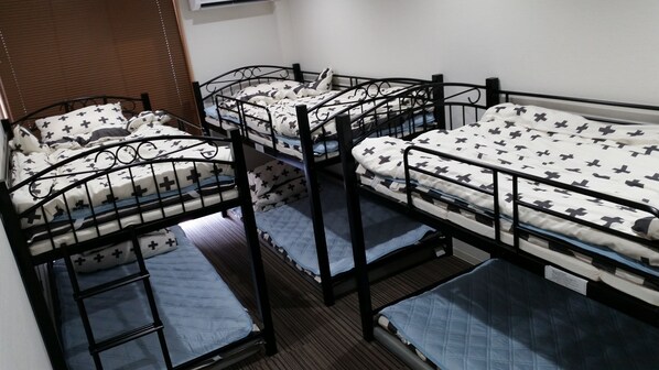 A dormitory room with four bunk beds, each with a patterned bedspread and pillows. - DK House - Hostel (Fukuoka)