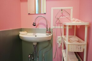 A bathroom with a sink, mirror, and a white shelf with a basket. - DK House - Hostel (Fukuoka)