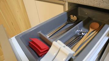 Uma gaveta com utensílios, incluindo um guardanapo vermelho, guardanapos brancos e utensílios de madeira.