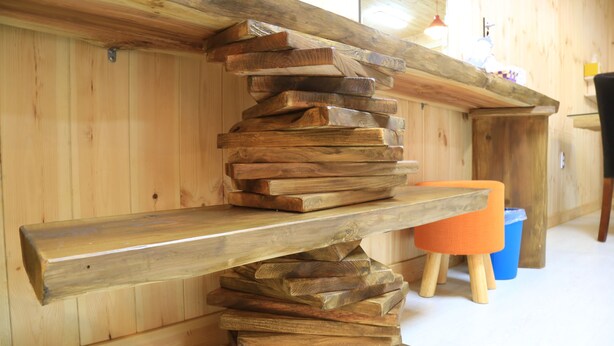 A wooden shelf with a stack of flat wooden planks. - Jeju Best Hill (Jeju City)