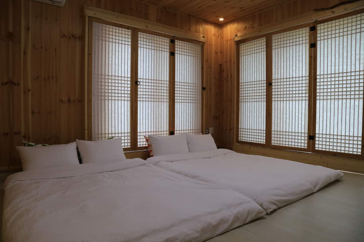 Een kamer met een groot bed, houten wanden en verschuifbare shoji-schermen.