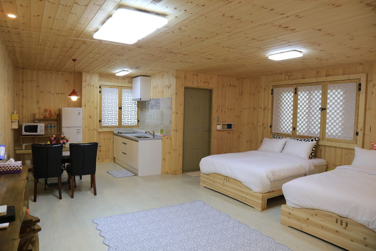 Een houten chalet met twee bedden, een keuken en een eethoek.