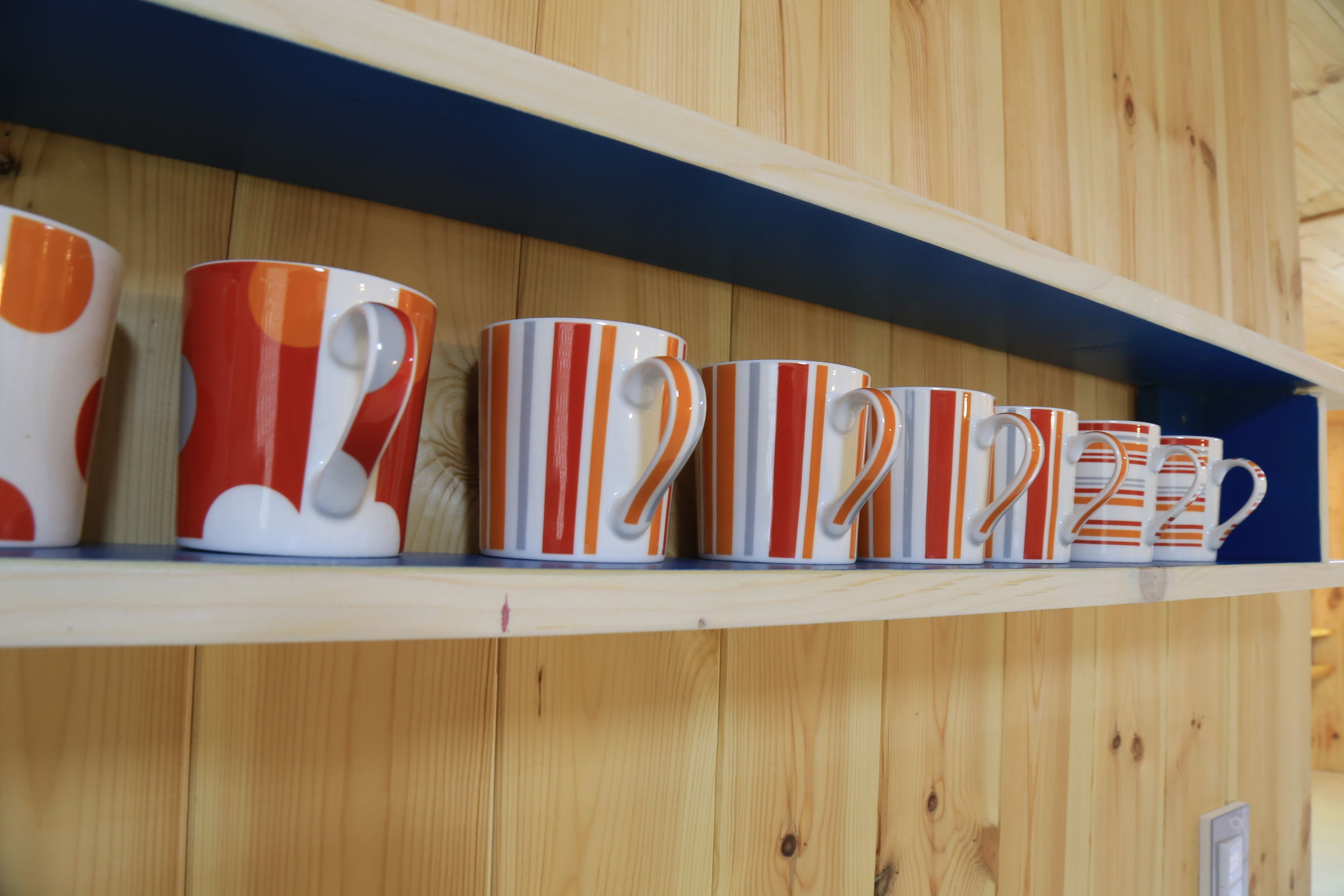A shelf with striped mugs.
