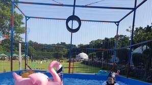 A swimming pool with inflatable toys, a safety fence, and a clear sky. - Jeju Best Hill (Jeju City)