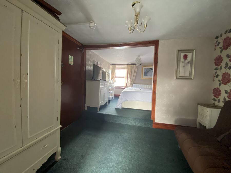 A hotel room with a bed, a dresser, a television, and a chandelier.