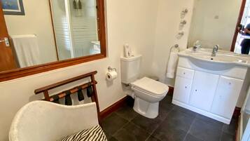 Un baño con un inodoro blanco, un lavamanos blanco y una silla con estampado de cebra.