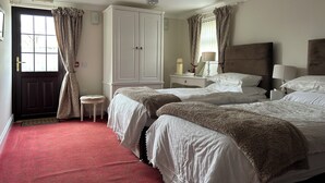 A hotel room with two beds, a wardrobe, a bedside table with a lamp, and a small stool. - Flambards Hotel (Cardigan)
