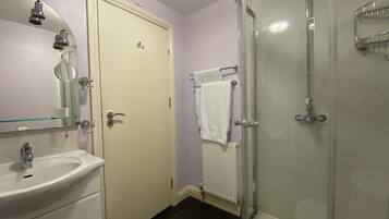 A bathroom with a glass-enclosed shower, a white sink, and a mirror above the sink.