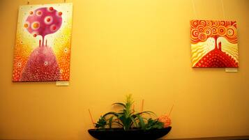 Two artworks on a wall, a potted plant in the foreground.