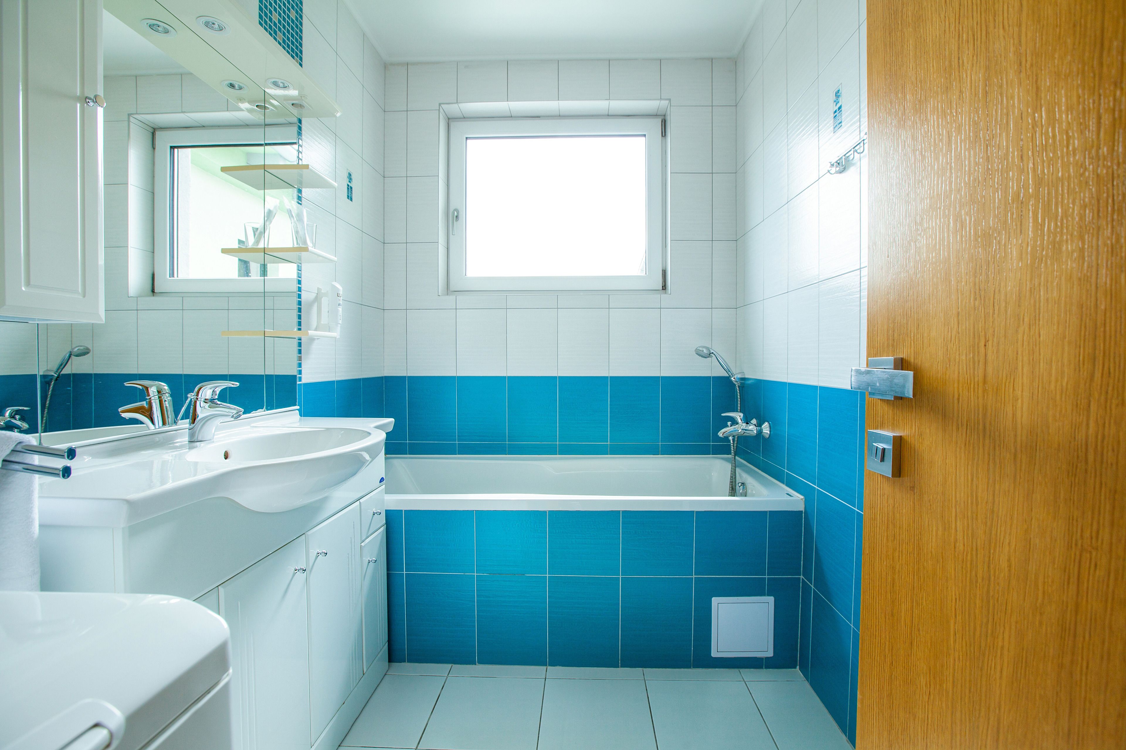 Un baño con un lavamanos blanco, una bañera y una ventana.