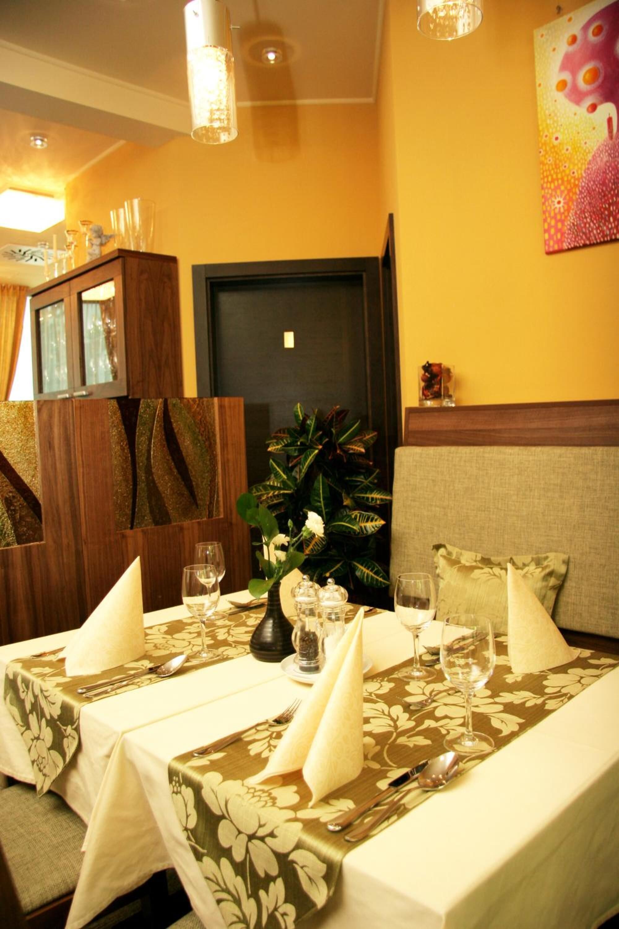 Une table à manger dressée avec des nappes blanches, des couverts en argent et de la verrerie.