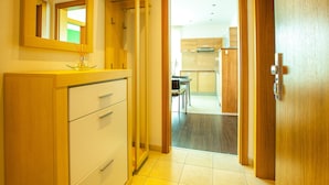 A hotel room with a wooden wardrobe, a mirror, and a view into the kitchen area. - Fine Restaurant & Apartments (Malacky)