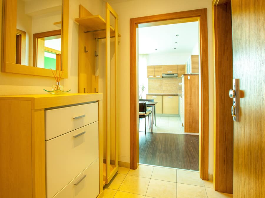 A hotel room with a wooden wardrobe, a mirror, and a view into the kitchen area.