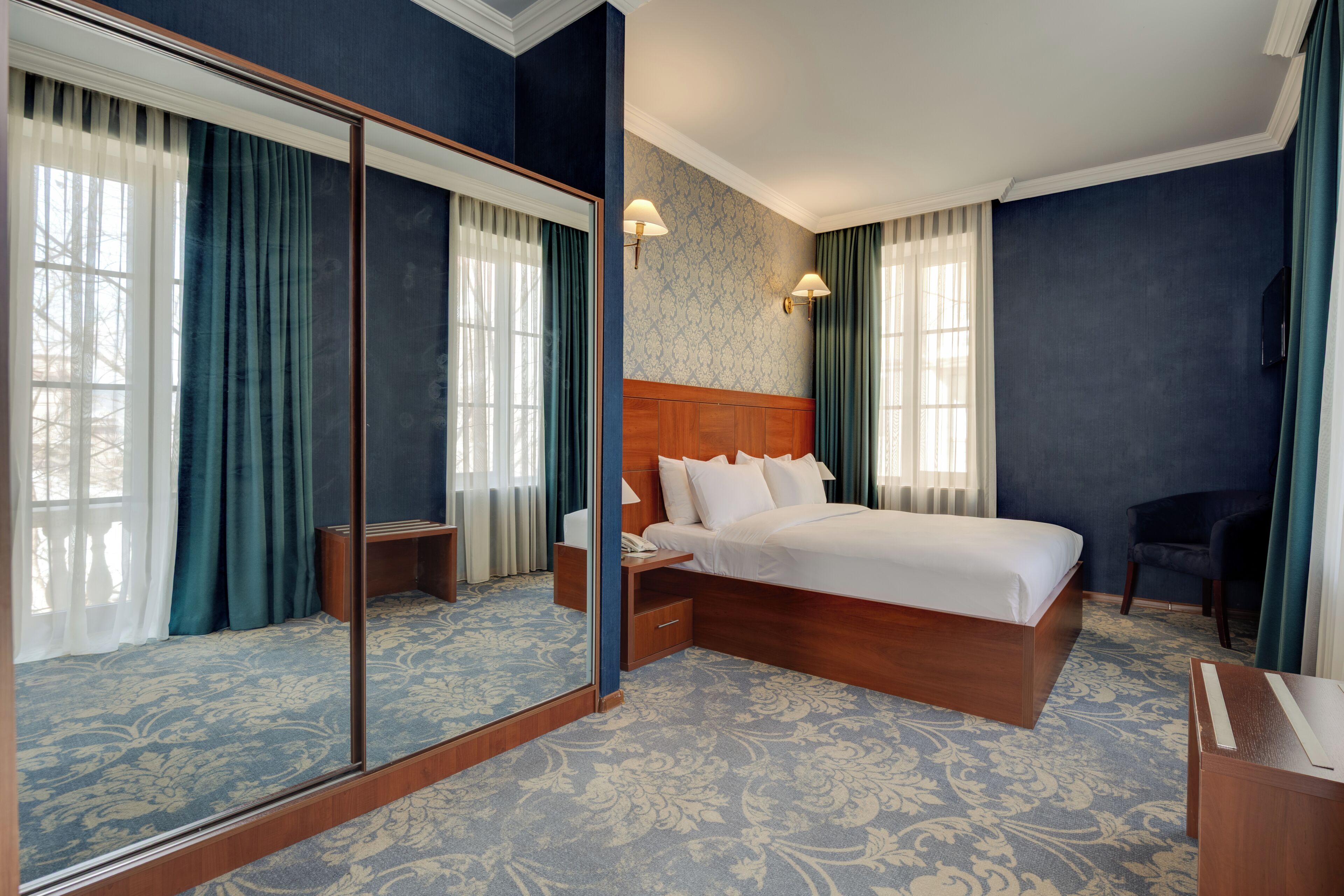Une chambre d’hôtel avec un grand lit, une table de chevet, un miroir et une chaise.
