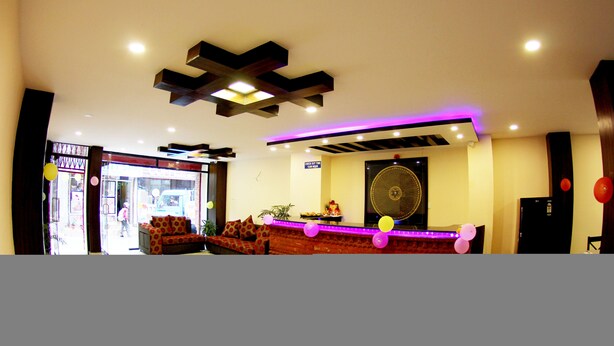 A reception area with a sofa, a decorative ceiling, and a sign.