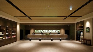 A spacious lobby with a reception desk, wooden shelving, and a modern ceiling design. - Hotel Monte Hermana Fukuoka (Fukuoka)