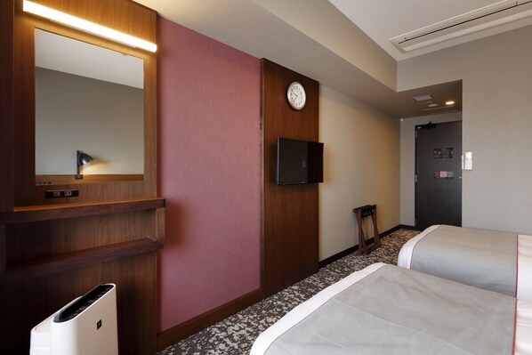 Una habitación de hotel con una cama, un espejo, un reloj, un televisor y un cubo de basura.