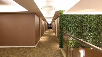 A hallway with a patterned carpet, wooden walls, and a green wall with foliage.