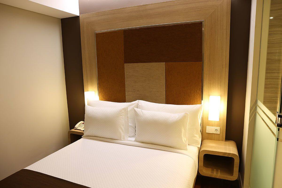 A neatly made bed with white linens and two bedside lamps.