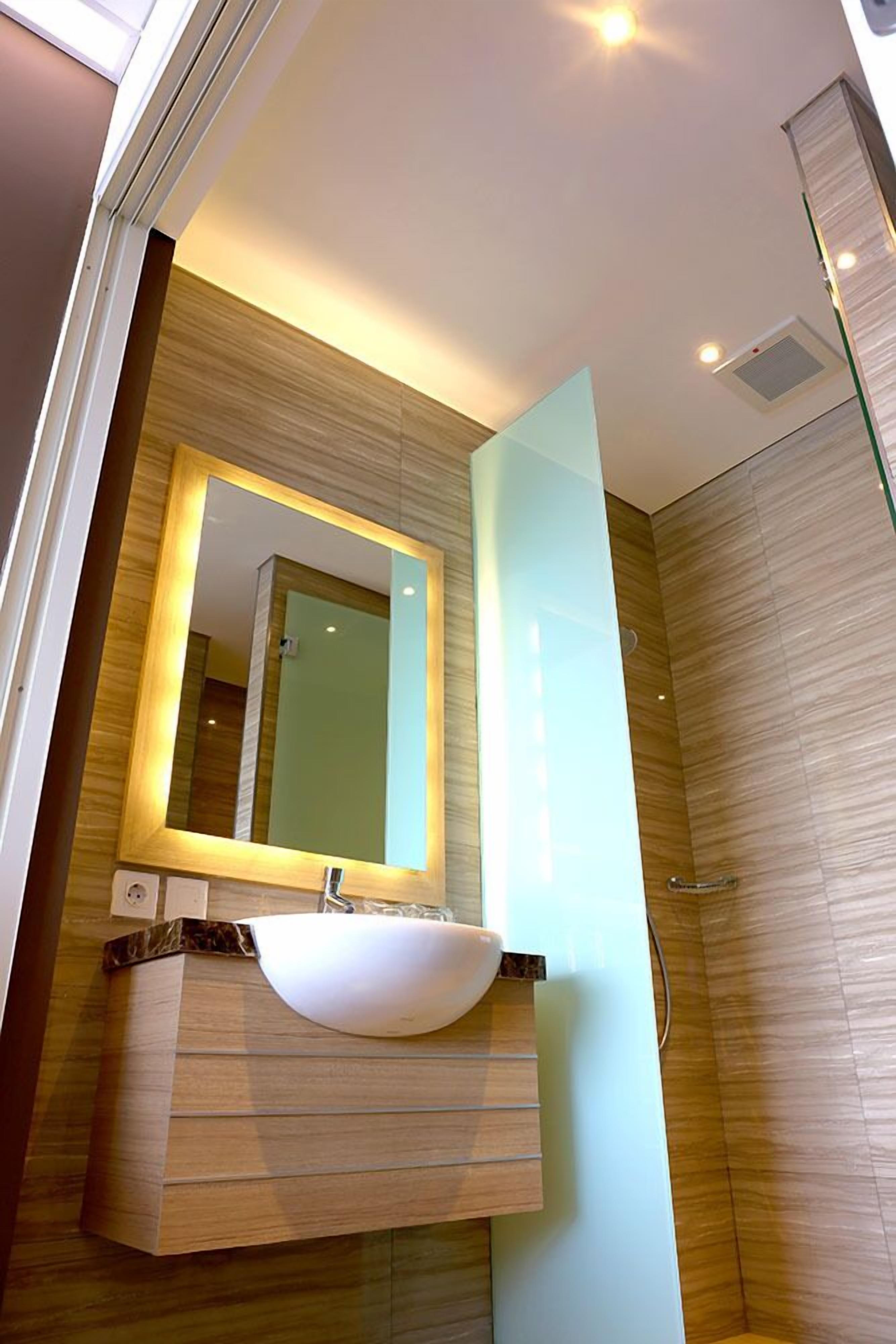 A modern bathroom with a large mirror, a white sink, and a glass shower enclosure.
