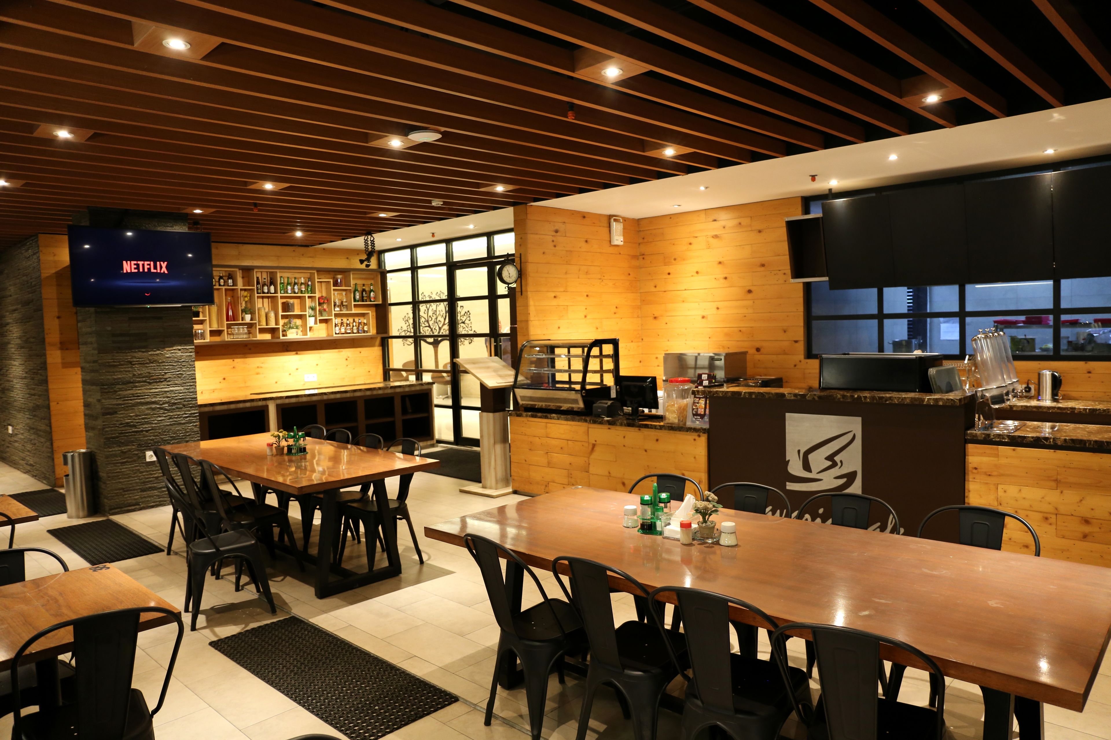 A restaurant with wooden walls, a bar area, and a television displaying 'NETFLIX'.