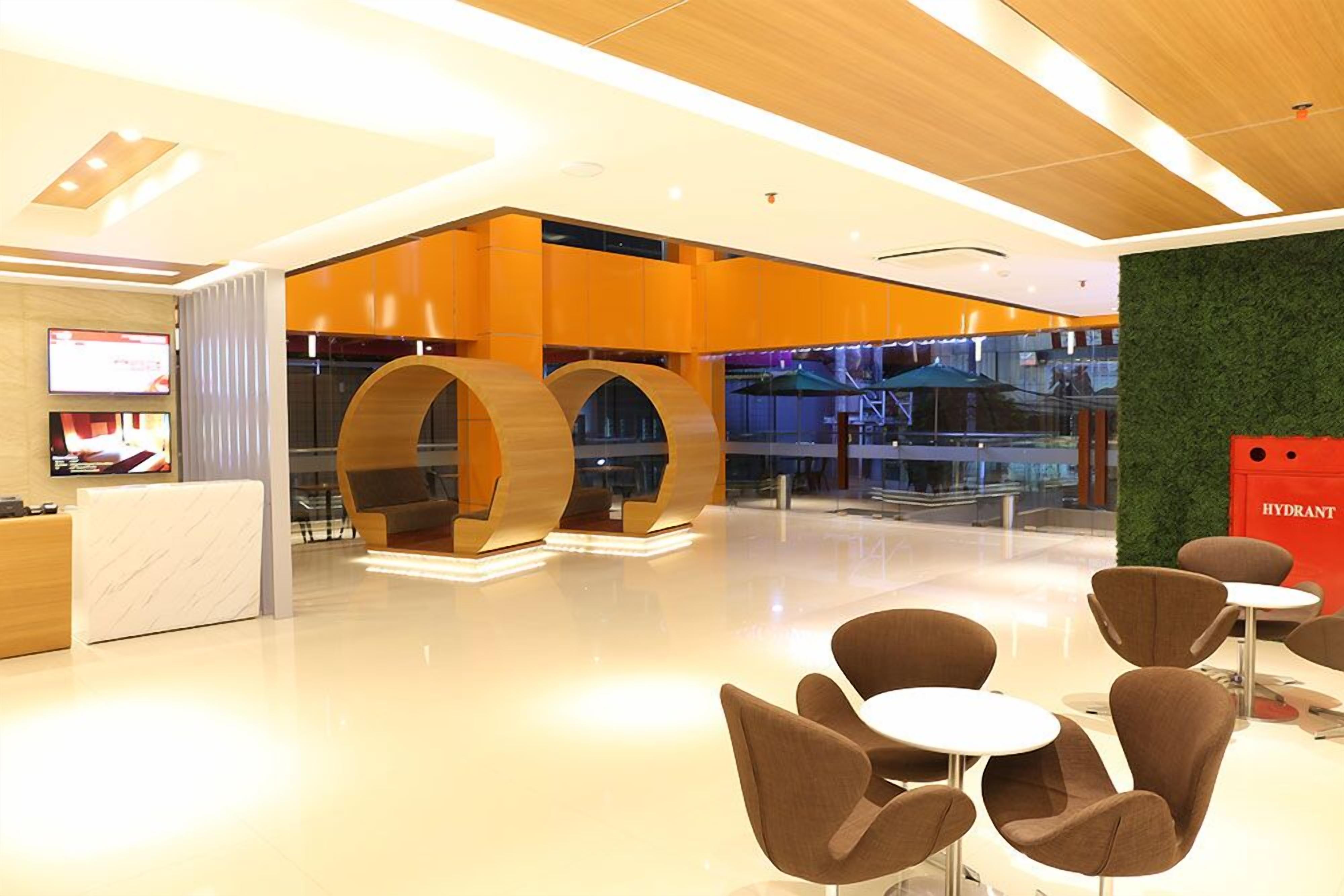 A modern lobby with a reception desk, seating area, and large wooden arches.