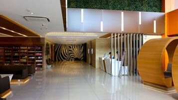 Een moderne lobby met een receptiebalie, zithoek en een muur met een weelderig, groen ontwerp.