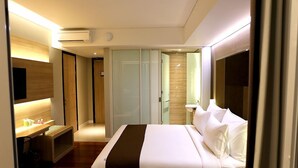 Una habitación de hotel moderna con una cama grande, un escritorio, una silla y un televisor.
