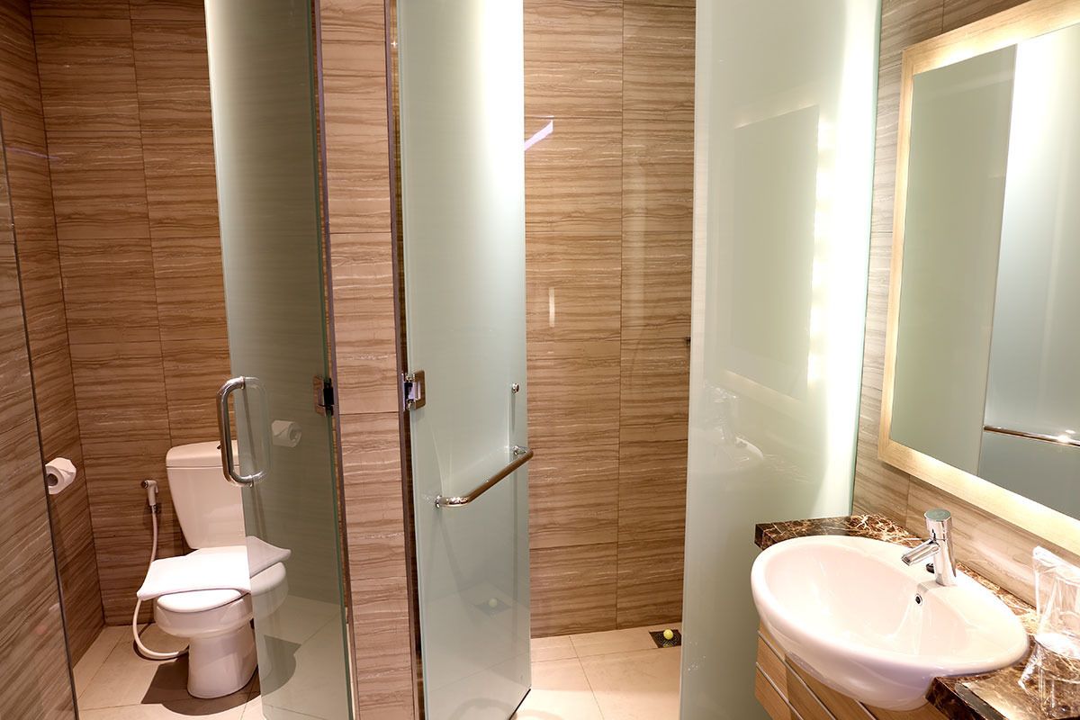 A modern bathroom with a glass-enclosed shower, a white toilet, and a marble countertop sink with a mirror.