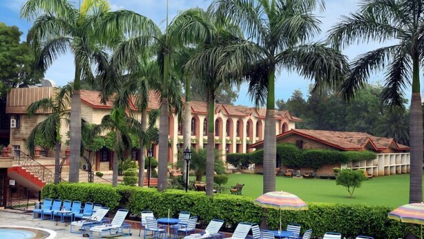 A resort with a pool area, lounge chairs, and palm trees. - Ashok Country Resort (New Delhi)