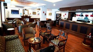 A restaurant with wooden furniture and a bar area. - Ashok Country Resort (New Delhi)