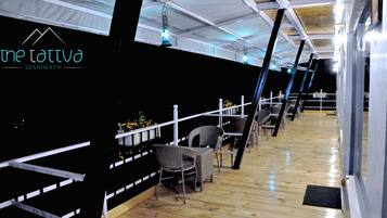 An indoor area with wooden flooring, metal railings, and wicker chairs.