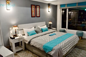 Una habitación de hotel moderna con una cama grande, dos mesitas de noche, una ventana con vistas y dos lámparas fijadas a la pared.