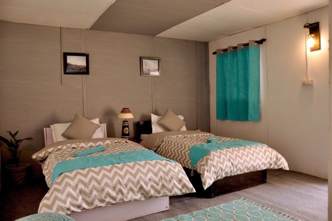 A room with two beds, a lamp, and a curtain.