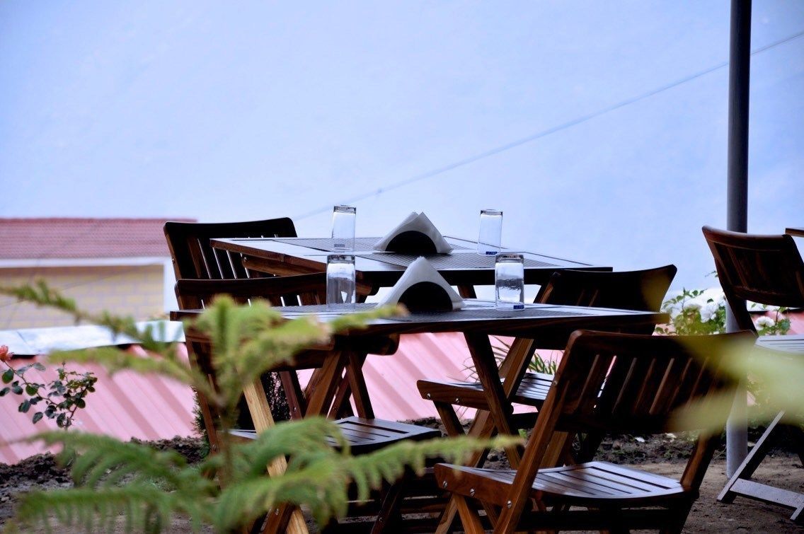 A wooden table with chairs, a water bottle, and a glass on it.