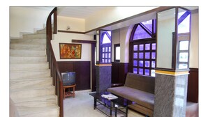 Uma sala de estar com escada, sofá, mesa de centro e um quadro na parede.