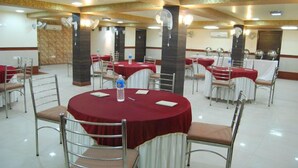Uma sala de conferências com mesas redondas, cadeiras e toalhas de mesa vermelhas.