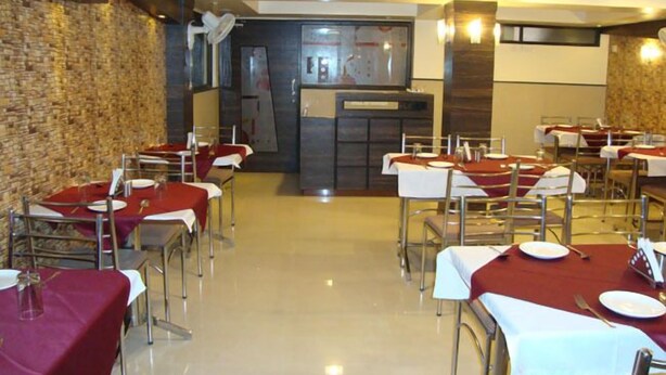 Um restaurante com mesas preparadas para refeições, uma parede de pedra e uma área de cozinha moderna.