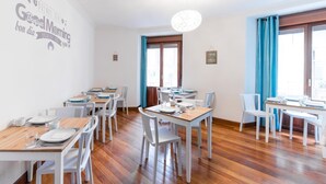 A dining area with multiple tables and chairs, wooden flooring, and a wall with a 'Good Morning' sign. - 7 Kale Bed and Breakfast (Bilbao)