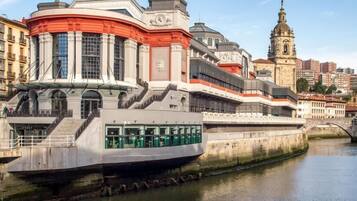 A modern building with a curved facade, a bridge, and a historic church in the background.