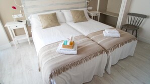 A double bed with two pillows, a bedside table with a remote control, and a small bedside table with a flower. - 7 Kale Bed and Breakfast (Bilbao)